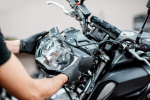 man repairing broken headlight on motorcycle